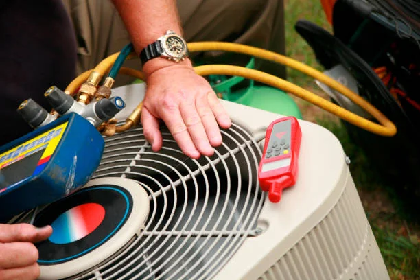 HVAC technician checking an outdoor condenser with gauges and a thermometer