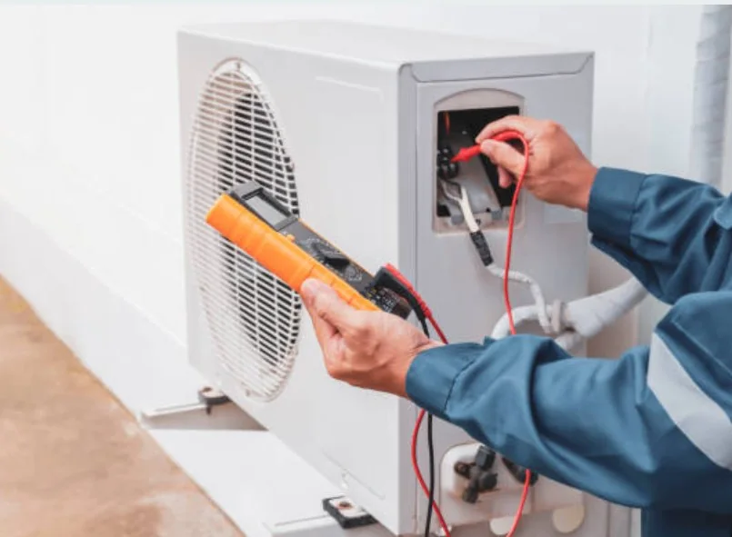 Technician using a multimeter to test an outdoor HVAC system