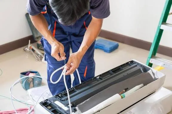 Technician servicing lines on an indoor air conditioning unit