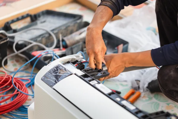 Technician repairing electrical components inside an air conditioning system