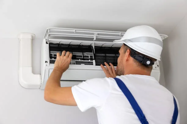 HVAC technician checking filters in a wall-mounted indoor unit
