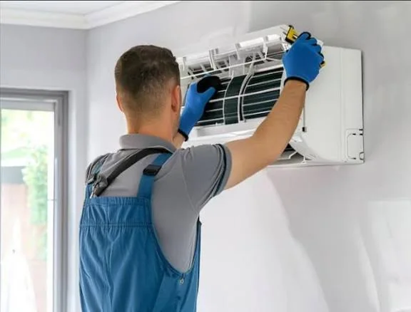 Technician installing the cover of a wall-mounted cooling unit